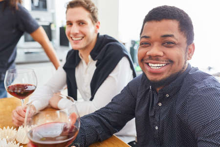 Group of men as friends together drinking wine on celebration in a shared kitchenの写真素材