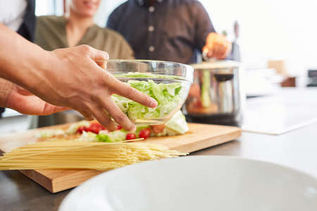 Preparing hands during lunch in kitchen with salad in bowl and spaghetti