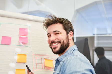 Self-confident founder in front of a flipchart with sticky notes and graphics