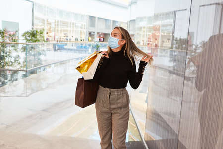 Woman as a customer with a mask because of Covid-19 in the shopping center while shoppingの写真素材