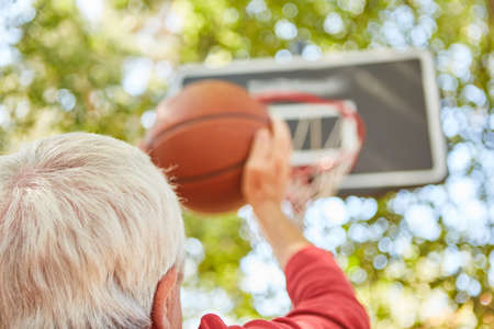 Senior man with ball concentrates on free throw while playing basketball in the gardenの写真素材