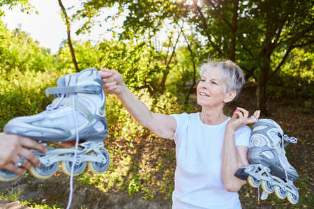 Vital senior woman with inline skates in nature in the summer before inline skatingの写真素材