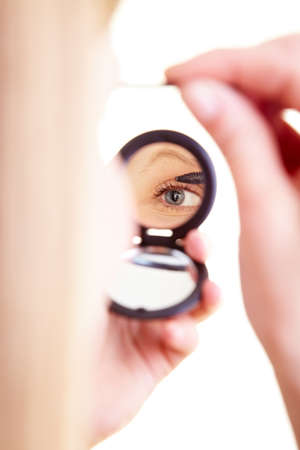 Blonde woman taps her eyelashes in the mirrorの写真素材