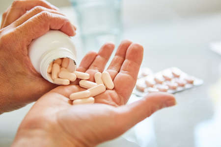 Patient pours many pills on his hand as a sign of drug addictionの写真素材