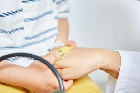 Doctor practices treatment with a plaster on the hand of the child as an exercise against fearの写真素材
