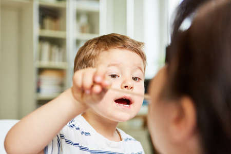 Child plays with spatula during consultation with a pediatrician or family doctorの写真素材