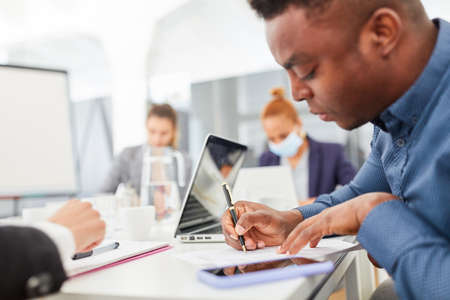 Young African as a trainee or student writes minutes in a meeting