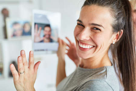 Happy young woman using tablet computer while video chat online with her partnerの写真素材
