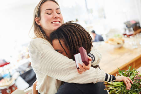 Happy woman in deep embrace with man after marriage proposal with wedding ring and bouquet