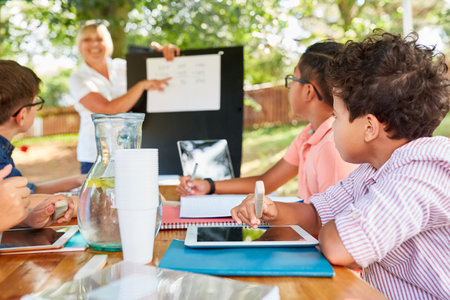 Woman as a teacher gives tutoring lessons for children in the summer school vacation course