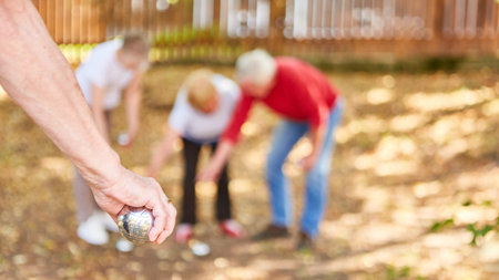 Hand of senior with bocce or boules ball at competition in the garden in summerの写真素材