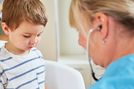 Anxious child as a patient with the pediatrician during the examination with the stethoscopeの写真素材