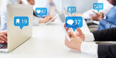 Business people with tablet and laptop computer use social media during meeting