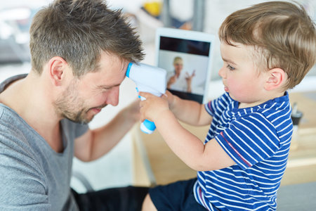 Boy measuring a fever with his father during the online consultation in the video chatの写真素材