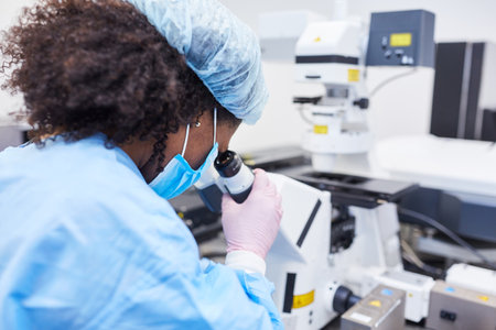 Researcher works on microscope in laboratory in Covid-19 pandemic looking for a vaccineの写真素材