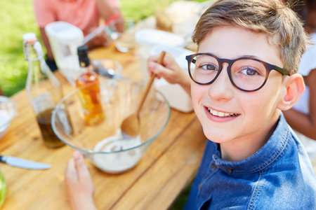 Happy boy preparing salad dressing in summer camp healthy eating cooking classの写真素材