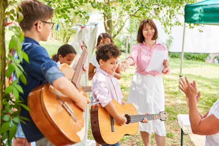 Group of children as a music band with guitars at talent show performance in summer campの写真素材