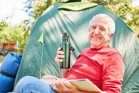 Happy senior with book and  relaxes while campingの写真素材
