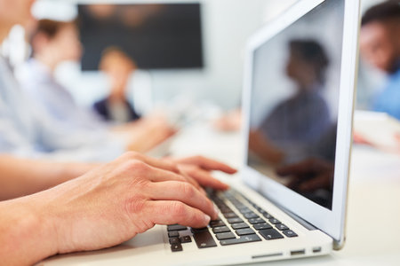 Hands of a business man typing on a laptop computer in a workshopの写真素材