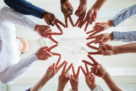 Hands of business people in circle make victory sign for success and synergyの写真素材