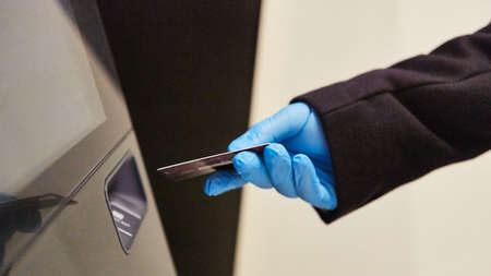 Customer withdrawing money from the ATM in latex gloves because of virusの写真素材