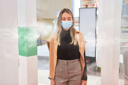 Customer with face mask during virus  disinfection at the entrance to the shopping center