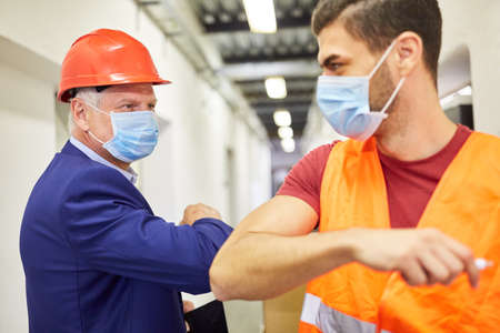 Boss and warehouse worker at an elbow greeting in the shipping companyの写真素材