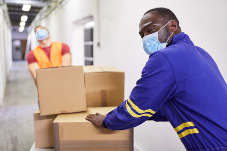 Workers with masks because of   push push carts with many packagesの写真素材