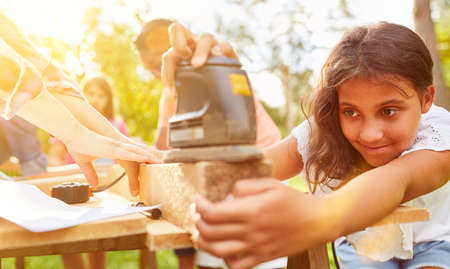 Girl sanding wood in works workshop at summer camp