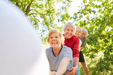 Group of vital seniors has fun in the strength competition on vacation in summer