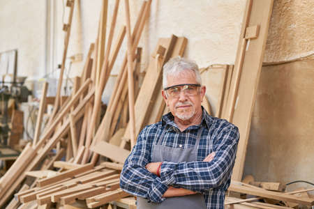Senior craftsman as a builder and proud boss in his carpentry workshopの写真素材