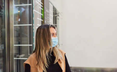 Woman as a saleswoman or employee in retail with mask because of Covid-19