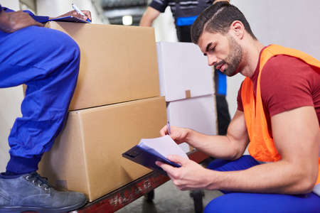 Warehouse clerk at the incoming goods department with a checklist when checking the delivery of...