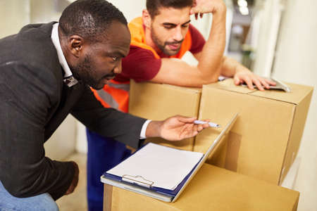Warehouse clerk and entrepreneur at the tablet computer with packages during online shipping