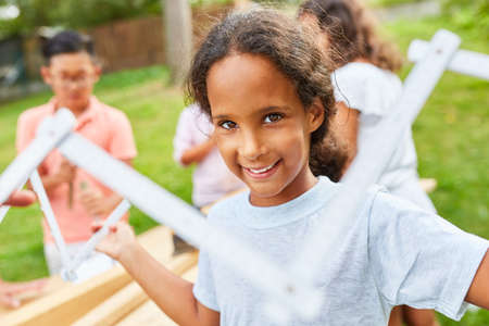 Girl plays with a folding rule in the craftsman workshop at summer campの写真素材