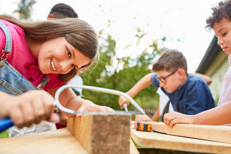Children work and do handicrafts with wood in the craftsman's workshop at the holiday campの写真素材
