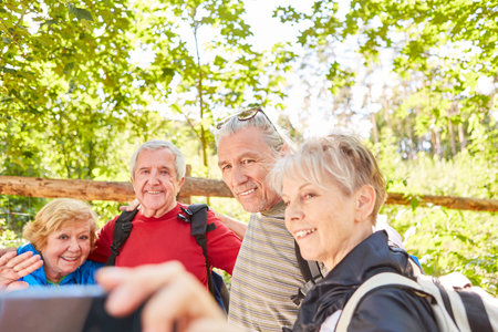 Senior hiking group makes a selfie with smartphone in nature in summerの写真素材