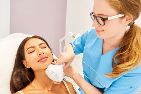 Young woman having skin tightening on her chin with the radio frequency in the beauty clinic