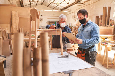 Two craftsmen with face masks because of Covid-19 as cabinet makers at work