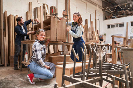 Craftsman apprentices as furniture makers glue a cabinet in the joineryの写真素材