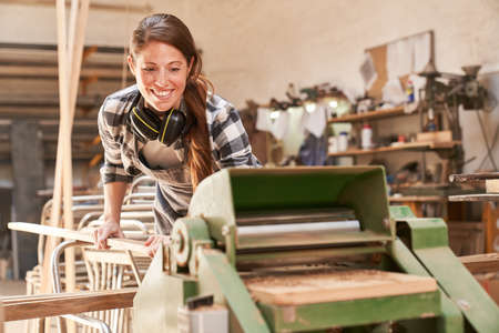 Craftsman woman at the thicknesser in the carpentry workshop