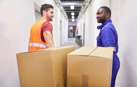Two workers as a multicultural team transporting packages to the warehouseの写真素材