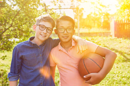 Two happy children with basketball together in summer at summer camp
