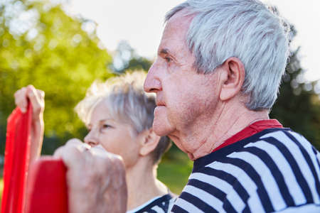 Couple of seniors with oars of rowing boat looks into the distance in summer at the lake