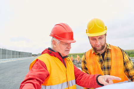 Architect and construction worker with architectural drawing when building a house or building a...