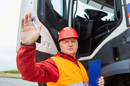 Worker as foreman or site manager on the truck gives hand signals on the construction site
