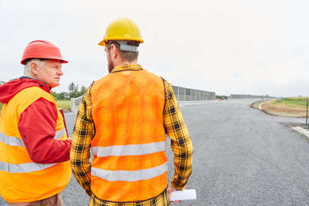 The architect and construction worker discuss upgrading or repairing the road at the construction siteの写真素材