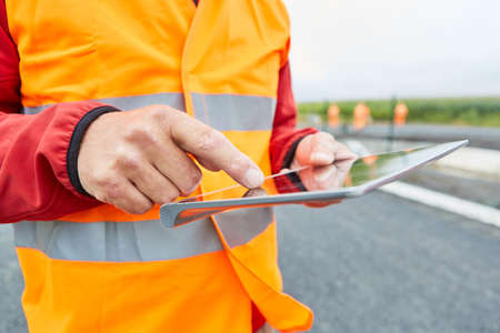 Construction worker using tablet computer during construction planning for house building or road...