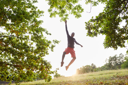 Young man makes a jump in the air in nature for freedom and joie de vivreの写真素材