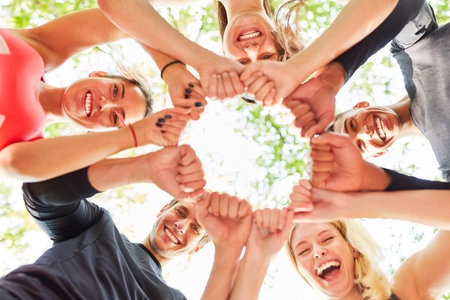 Group of young people as a team with clenched fists in a circle for team building